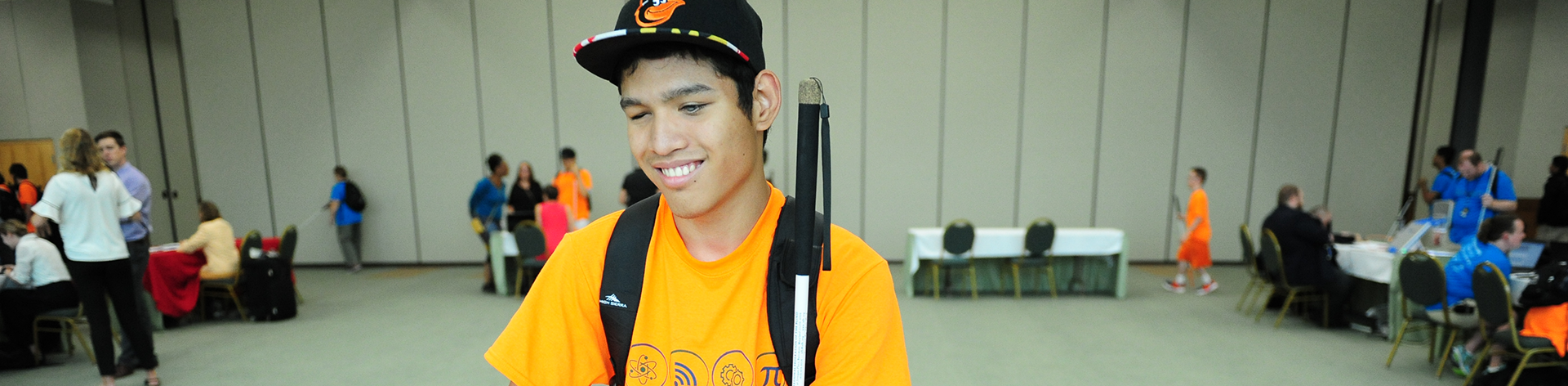 A blind teen smiles with his cane resting on his shoulder.