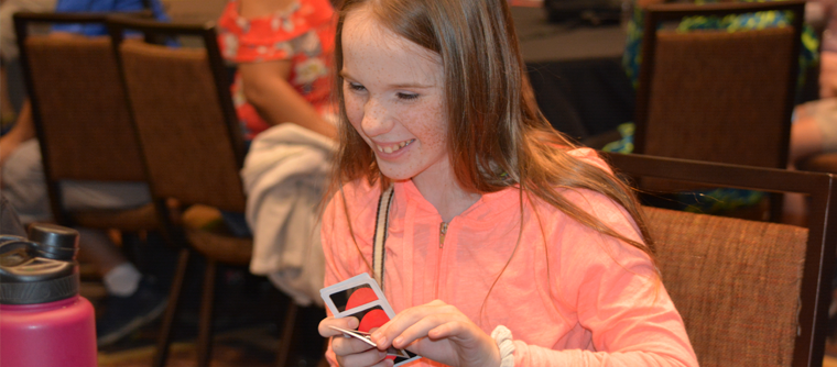 A smiling blind girl plays UNO with Braille UNO cards.