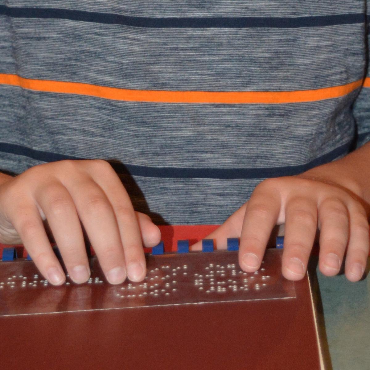 small child hands reading braille.